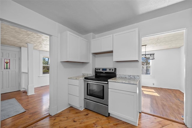 kitchen with light stone counters, light wood finished floors, white cabinets, and stainless steel electric stove