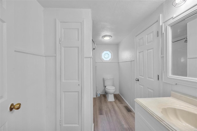 bathroom featuring toilet, visible vents, wood finished floors, and vanity