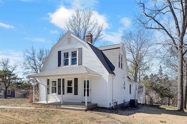 dutch colonial with a porch, central AC, a gambrel roof, roof with shingles, and a chimney