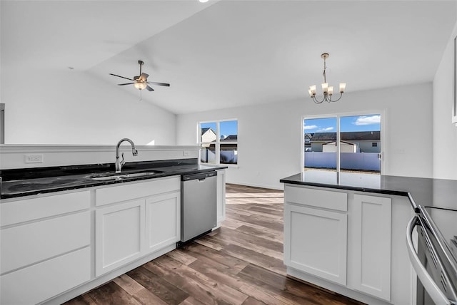 kitchen with dark countertops, appliances with stainless steel finishes, white cabinetry, a sink, and wood finished floors