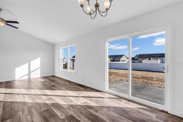 unfurnished living room with baseboards, vaulted ceiling, wood finished floors, and ceiling fan with notable chandelier