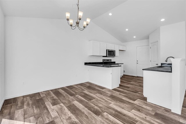 kitchen with a peninsula, white cabinets, appliances with stainless steel finishes, dark wood-style floors, and dark countertops