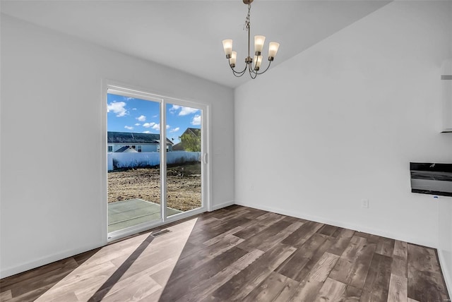 unfurnished dining area featuring a chandelier, baseboards, and wood finished floors