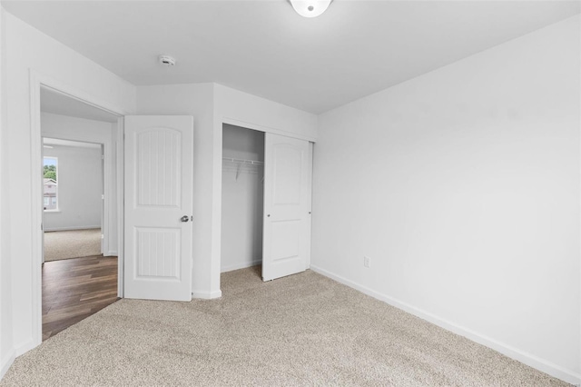 unfurnished bedroom with a closet, carpet flooring, and baseboards