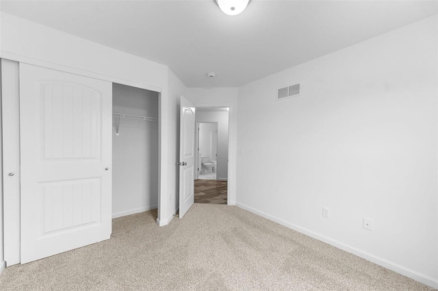 unfurnished bedroom with baseboards, a closet, visible vents, and light colored carpet