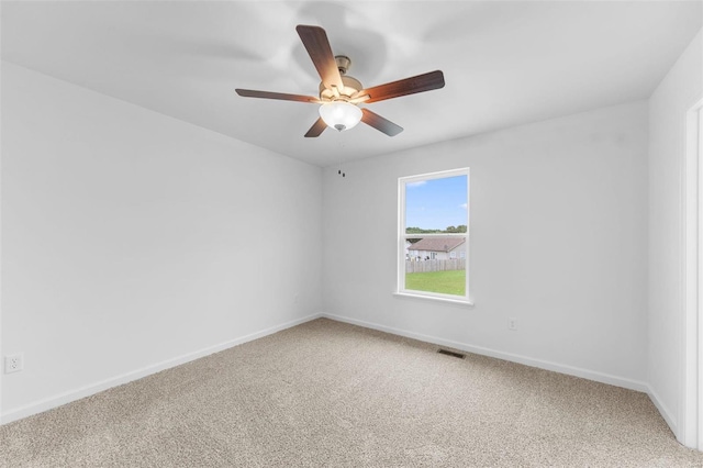 carpeted spare room with baseboards, visible vents, and ceiling fan