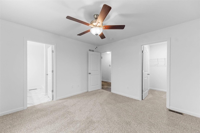 unfurnished bedroom featuring carpet floors, ensuite bath, a spacious closet, and baseboards