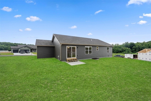 rear view of property featuring entry steps, a yard, and roof with shingles