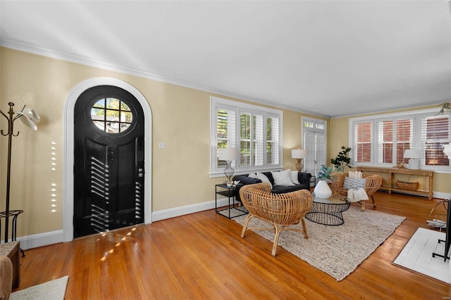 entrance foyer with arched walkways, ornamental molding, wood finished floors, and baseboards