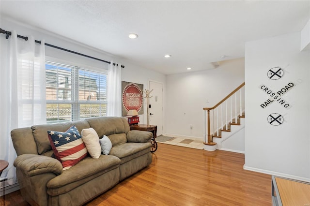 living room with recessed lighting, light wood-style flooring, baseboards, and stairs