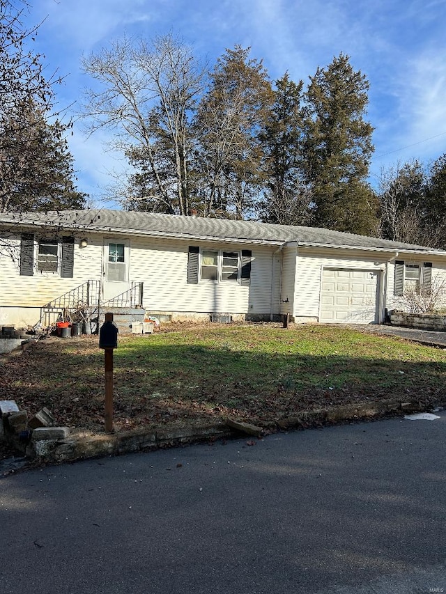 ranch-style home with a front lawn, a garage, and driveway