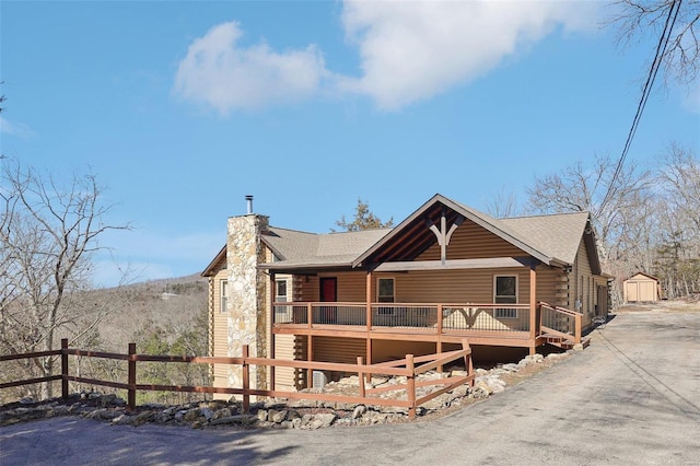 exterior space with log exterior, a chimney, a deck, and fence