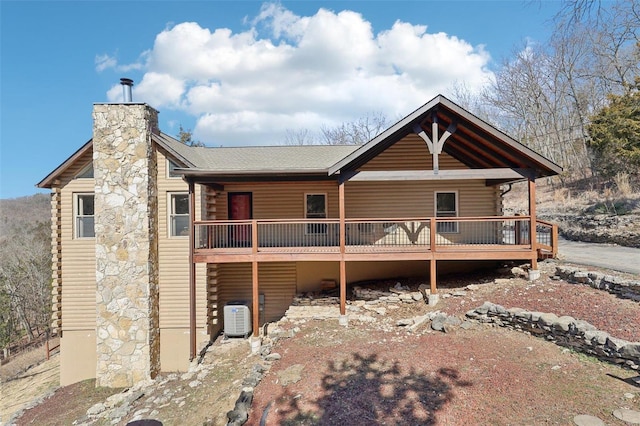 rear view of property featuring cooling unit, log exterior, and a chimney