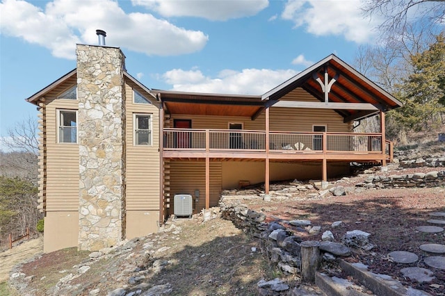 rear view of house featuring a wooden deck, central air condition unit, and a chimney