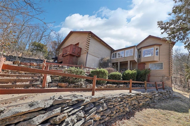 view of front of house featuring a balcony, log exterior, and fence