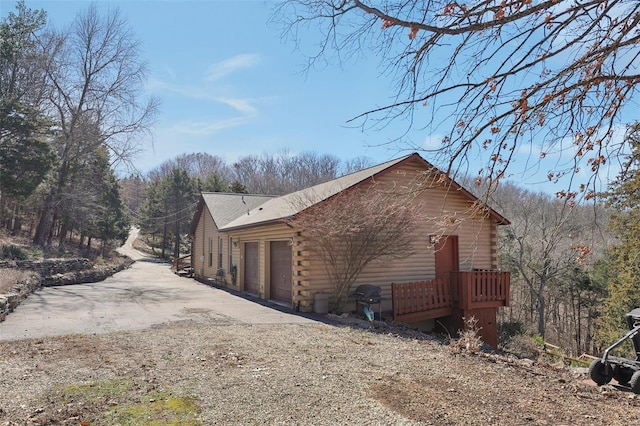 view of property exterior with log exterior, a garage, and driveway