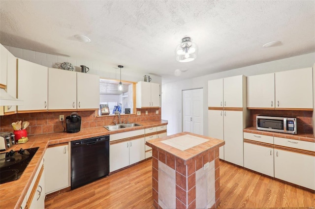 kitchen featuring a sink, black appliances, light wood-style floors, white cabinetry, and backsplash