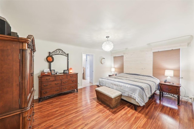 bedroom with an inviting chandelier, wood finished floors, and baseboards