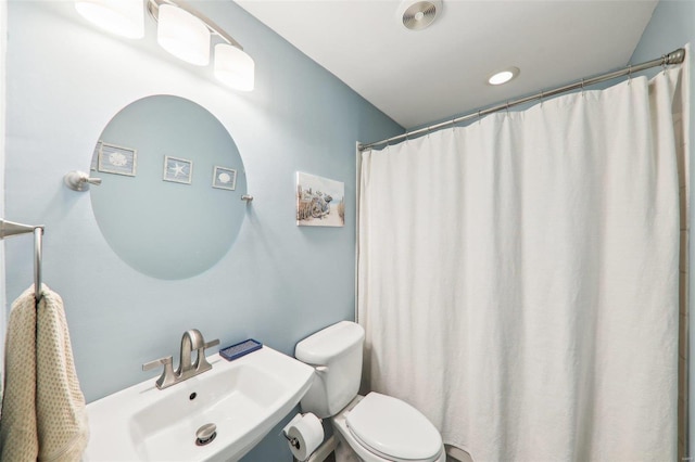 bathroom featuring a shower with curtain, toilet, and a sink