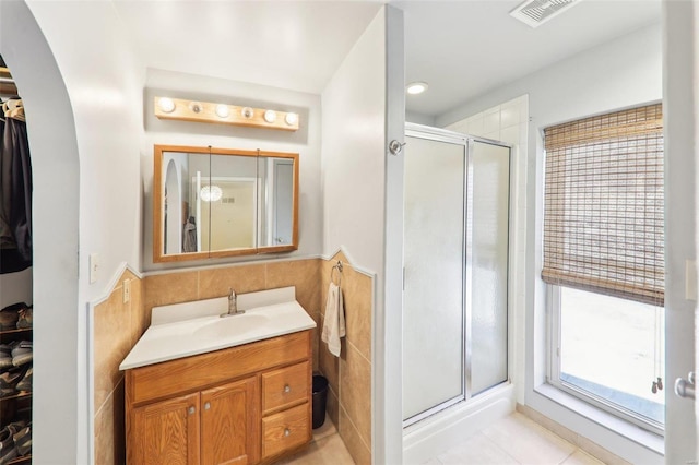 full bath with vanity, visible vents, tile patterned flooring, a shower stall, and tile walls