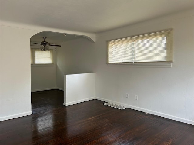 unfurnished room featuring a ceiling fan, visible vents, arched walkways, and wood finished floors