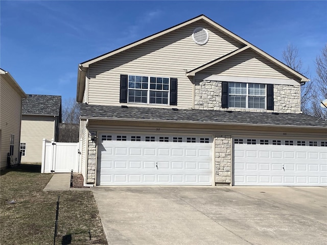 traditional home with an attached garage, stone siding, a gate, and concrete driveway