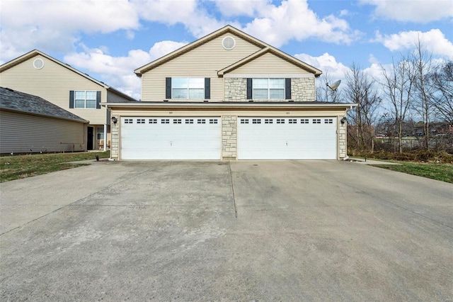 traditional home featuring stone siding, an attached garage, and driveway