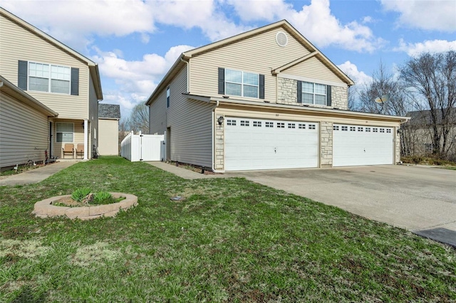 view of front of home featuring fence, a front yard, stone siding, driveway, and a gate