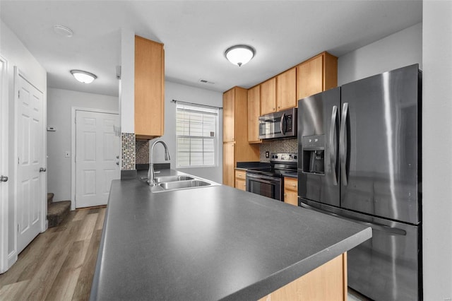 kitchen with a sink, decorative backsplash, dark countertops, and appliances with stainless steel finishes