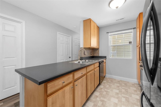 kitchen with dark countertops, visible vents, a peninsula, freestanding refrigerator, and a sink