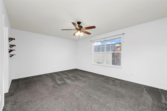 empty room featuring dark colored carpet, baseboards, and ceiling fan