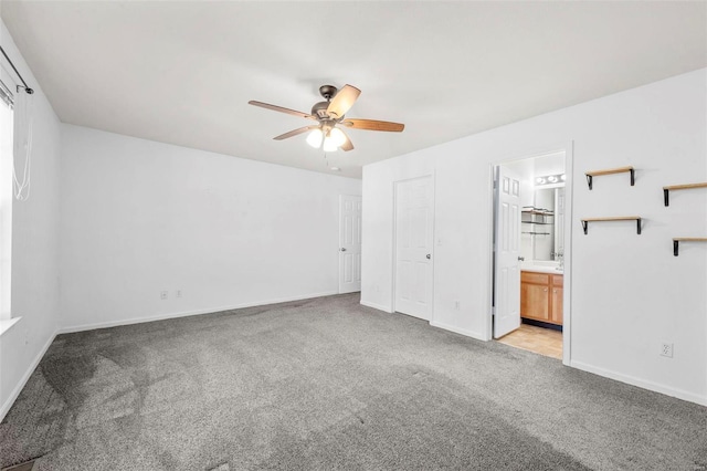 interior space featuring light colored carpet, baseboards, and ceiling fan