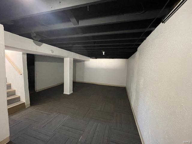 finished below grade area featuring stairs and a textured wall