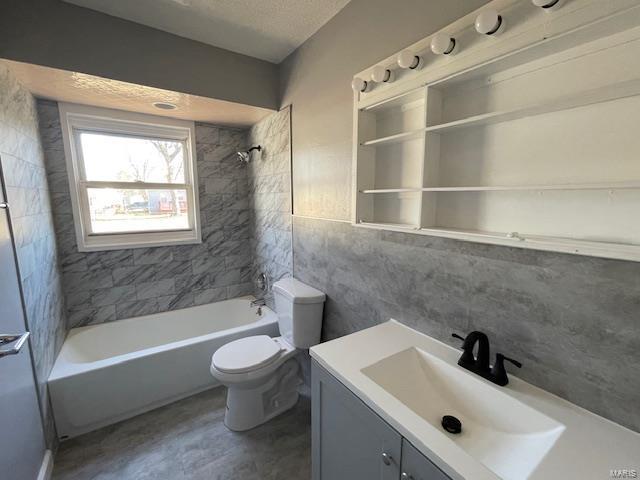 bathroom featuring tile walls, tub / shower combination, vanity, and toilet