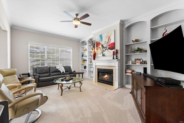 living room featuring light carpet, ornamental molding, a glass covered fireplace, and a ceiling fan