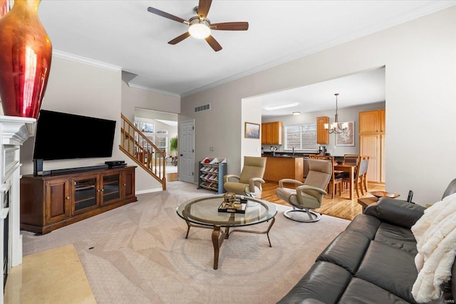 living room with ceiling fan with notable chandelier, visible vents, a healthy amount of sunlight, stairway, and crown molding