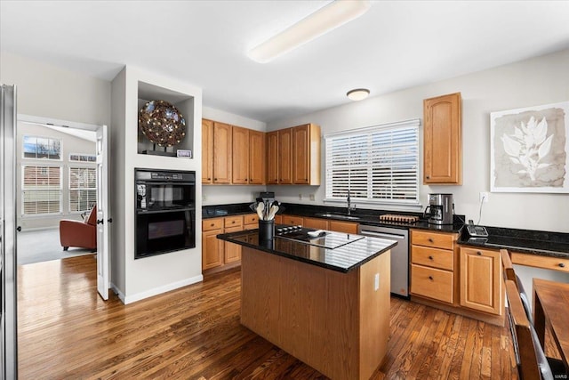 kitchen featuring dark wood finished floors, a kitchen island, a sink, dark stone counters, and black appliances