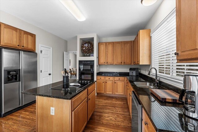 kitchen with dark stone counters, black appliances, dark wood-type flooring, and a sink