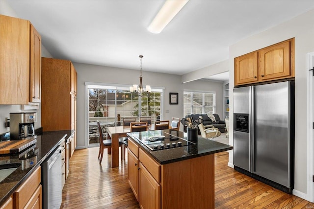 kitchen with appliances with stainless steel finishes, dark stone counters, and wood-type flooring