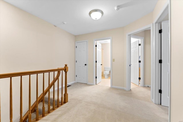 corridor with light carpet, an upstairs landing, and baseboards