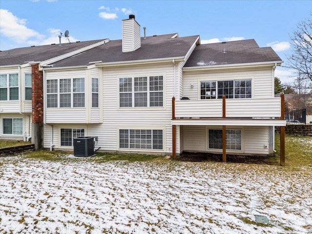 back of house with central AC unit and a chimney