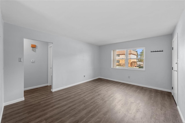 unfurnished room with dark wood-type flooring and baseboards