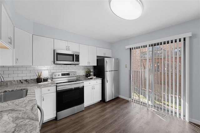 kitchen with visible vents, a sink, dark wood-type flooring, appliances with stainless steel finishes, and tasteful backsplash