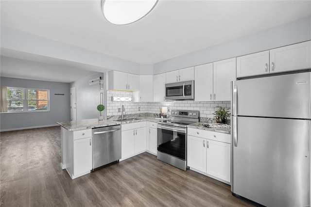 kitchen featuring decorative backsplash, white cabinets, appliances with stainless steel finishes, and a sink