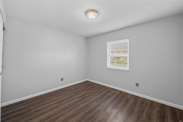 unfurnished room featuring dark wood-style floors, baseboards, and visible vents