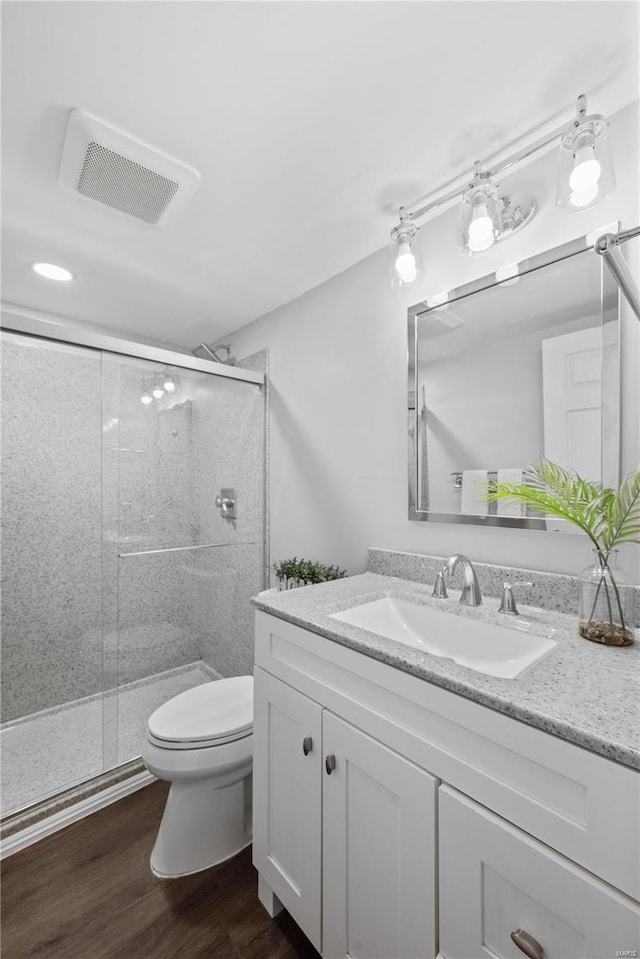 full bath featuring visible vents, toilet, wood finished floors, a shower stall, and vanity