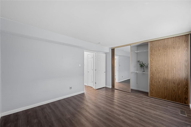 unfurnished bedroom featuring a closet, visible vents, dark wood-type flooring, and baseboards