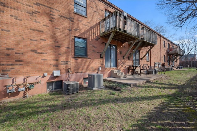 back of house featuring central air condition unit, brick siding, a lawn, and entry steps