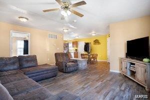 living room featuring a ceiling fan, baseboards, visible vents, and wood finished floors