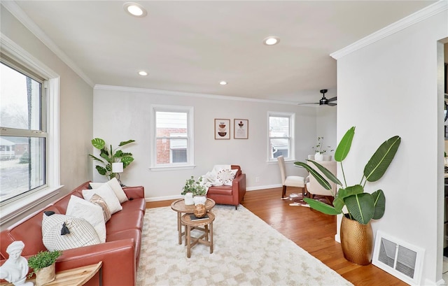 living room with ornamental molding, a wealth of natural light, visible vents, and wood finished floors